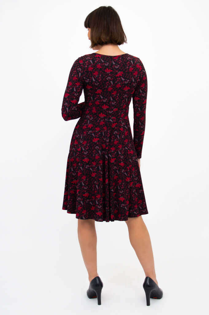 Back view of woman in black and red floral fit and flare dress with long sleeves
