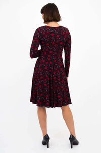 Back view of woman in black and red floral fit and flare dress with long sleeves
