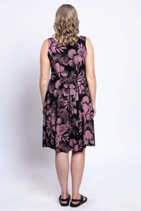 Back view of woman in black dress with pink floral details and tied belt