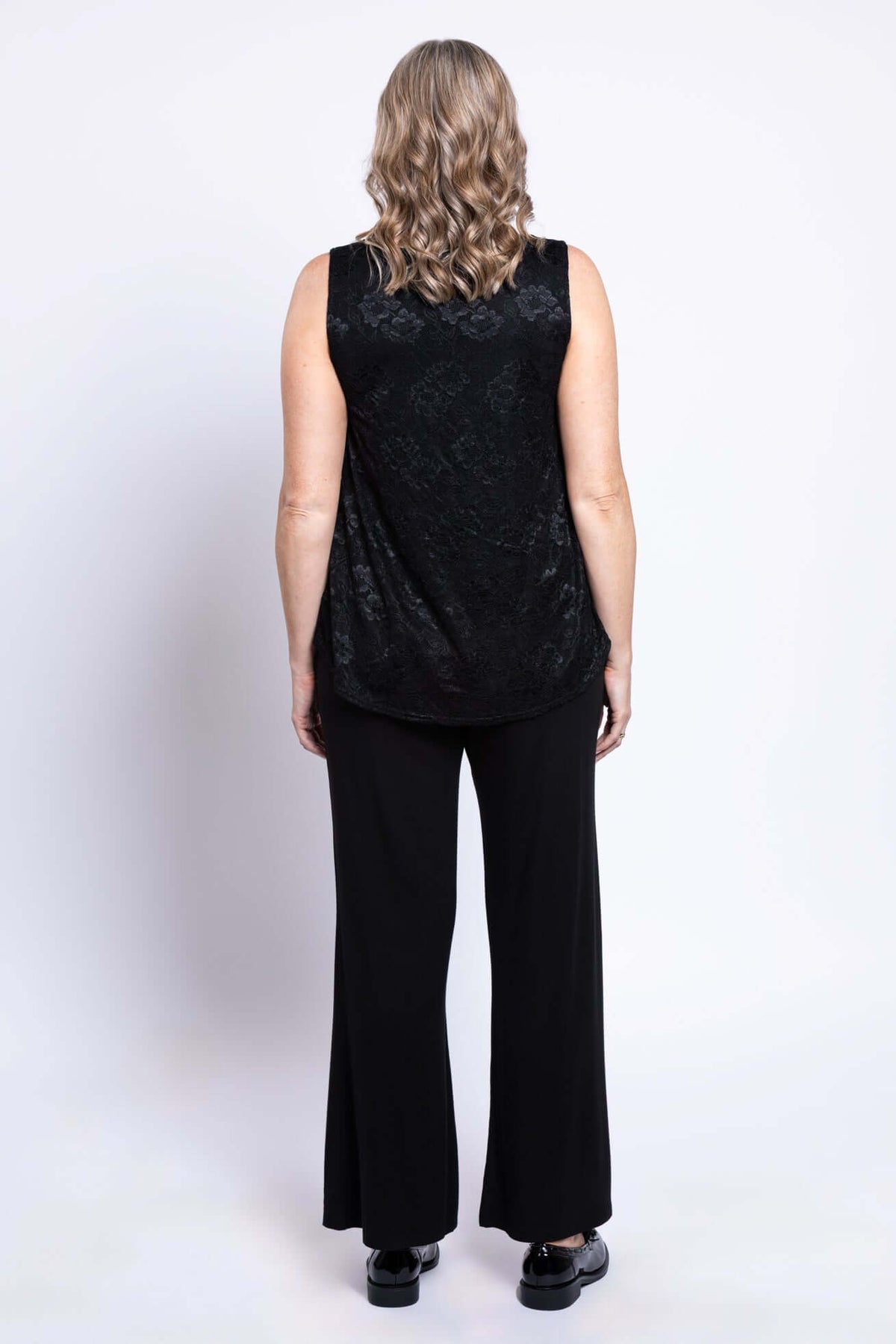 Back view of a woman wearing a sleeveless black lace tank top and pants