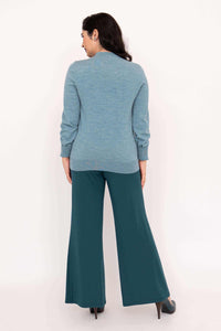 Back view of woman in blue cardigan and teal pants