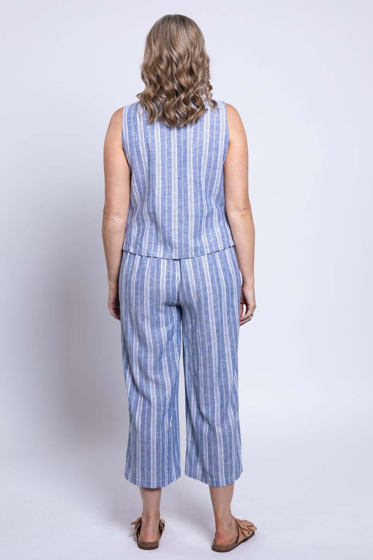 Back view of woman wearing matching blue striped sleeveless top and cropped capri pants