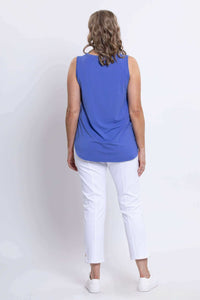 Back full body view of woman wearing hip-length blue sleeveless top and white capri pants