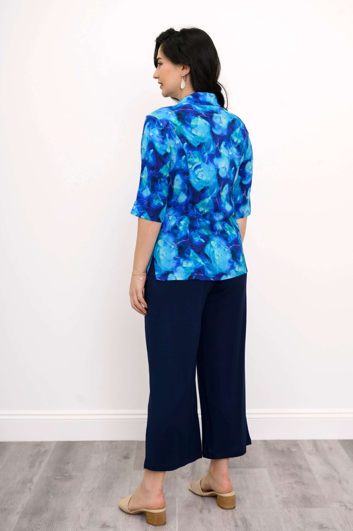 Back view of woman in blue watercolor blouse and navy wide-leg pants