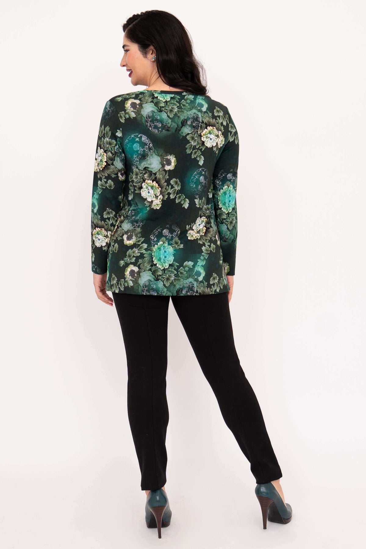 Back view of woman wearing green floral long sleeve top and black pants