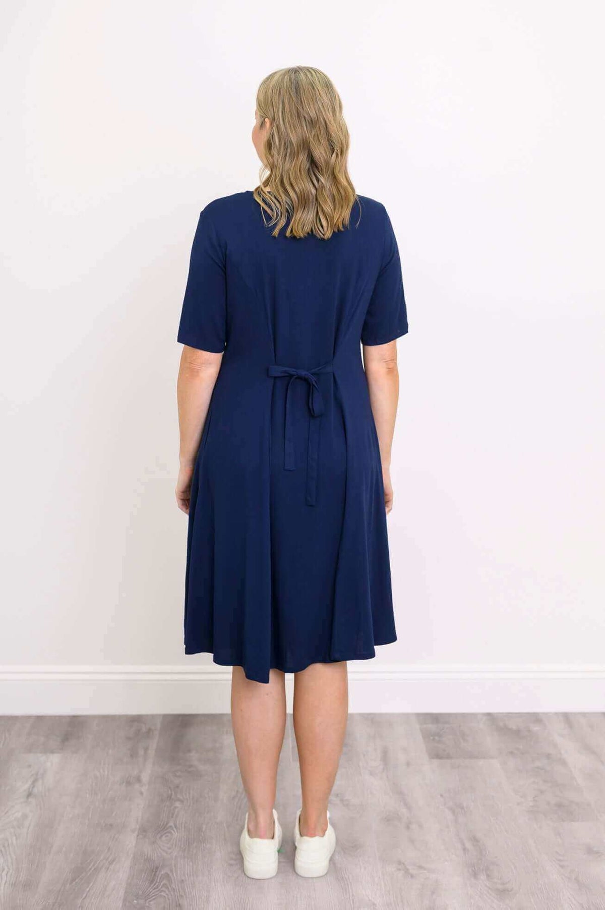 Back view of woman in navy dress with tie belt and short sleeves