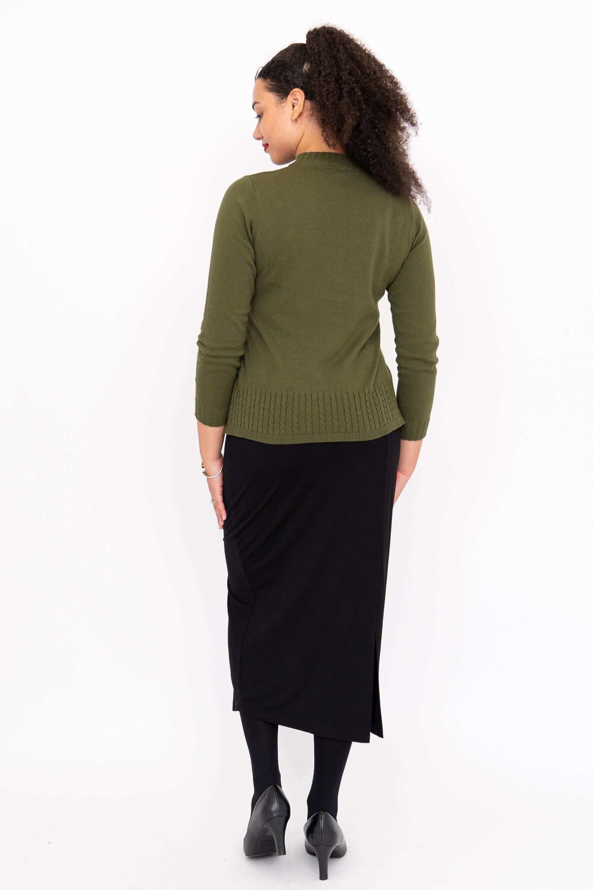 Back view of a woman in an olive green sweater and black skirt