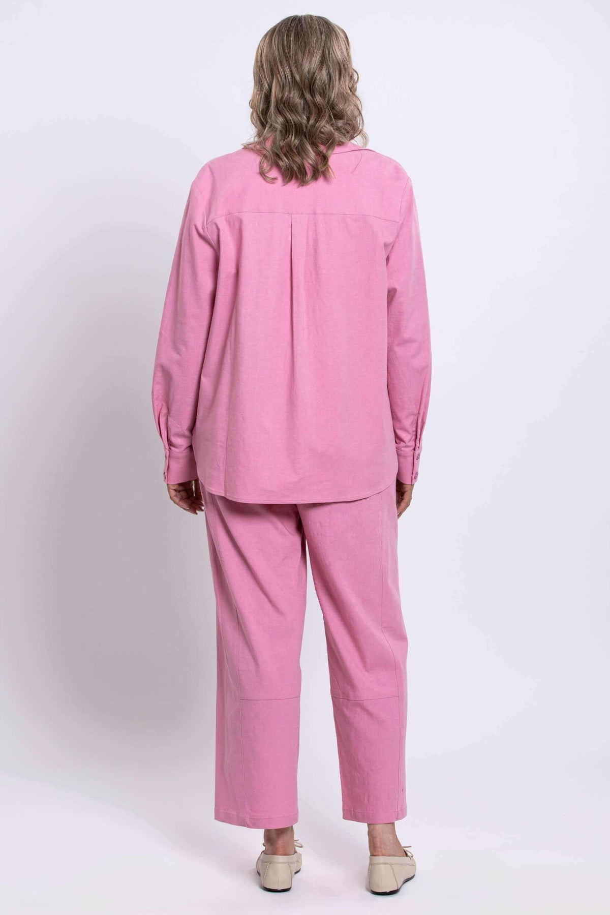 Back view of a woman wearing a pink linen blend shirt and pants set