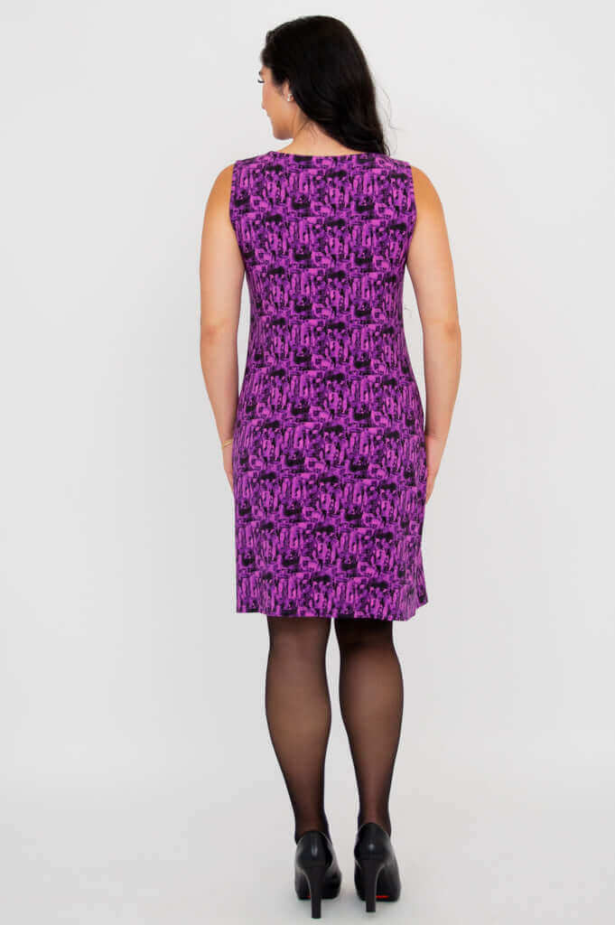 Back view of woman wearing a purple patterned shift dress and black heels