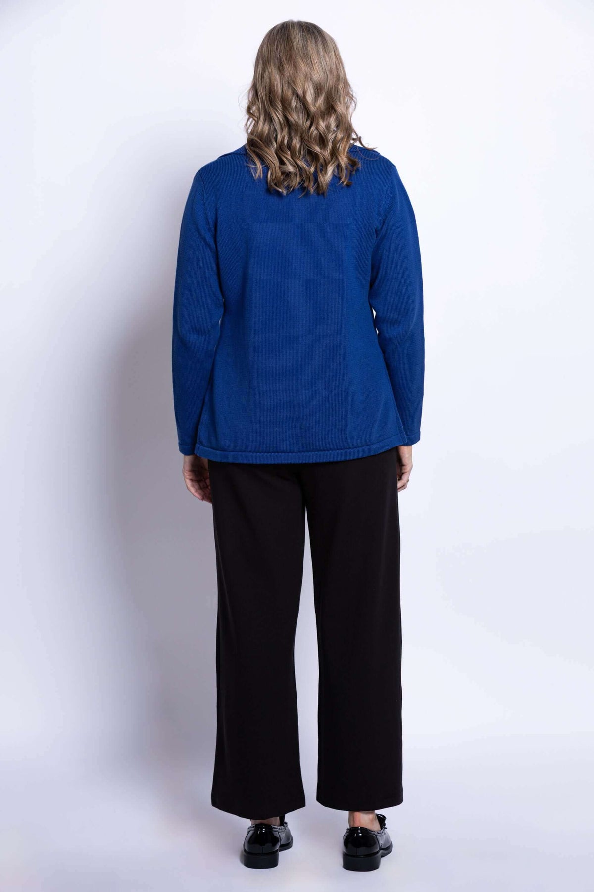 Back view of woman wearing royal blue Lily Cardigan and loose black pants
