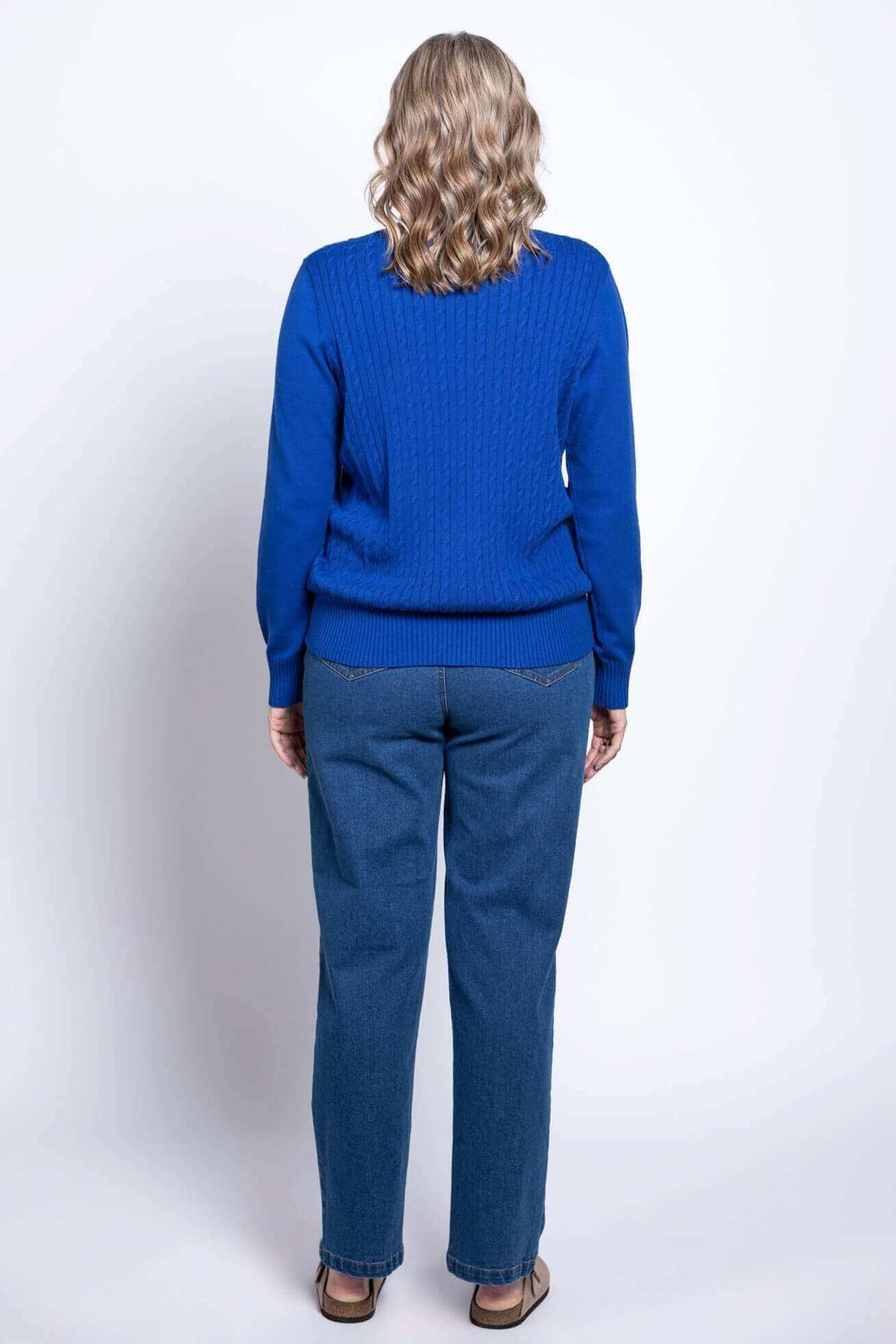 Back view of woman wearing a royal blue cable knit sweater and blue jeans