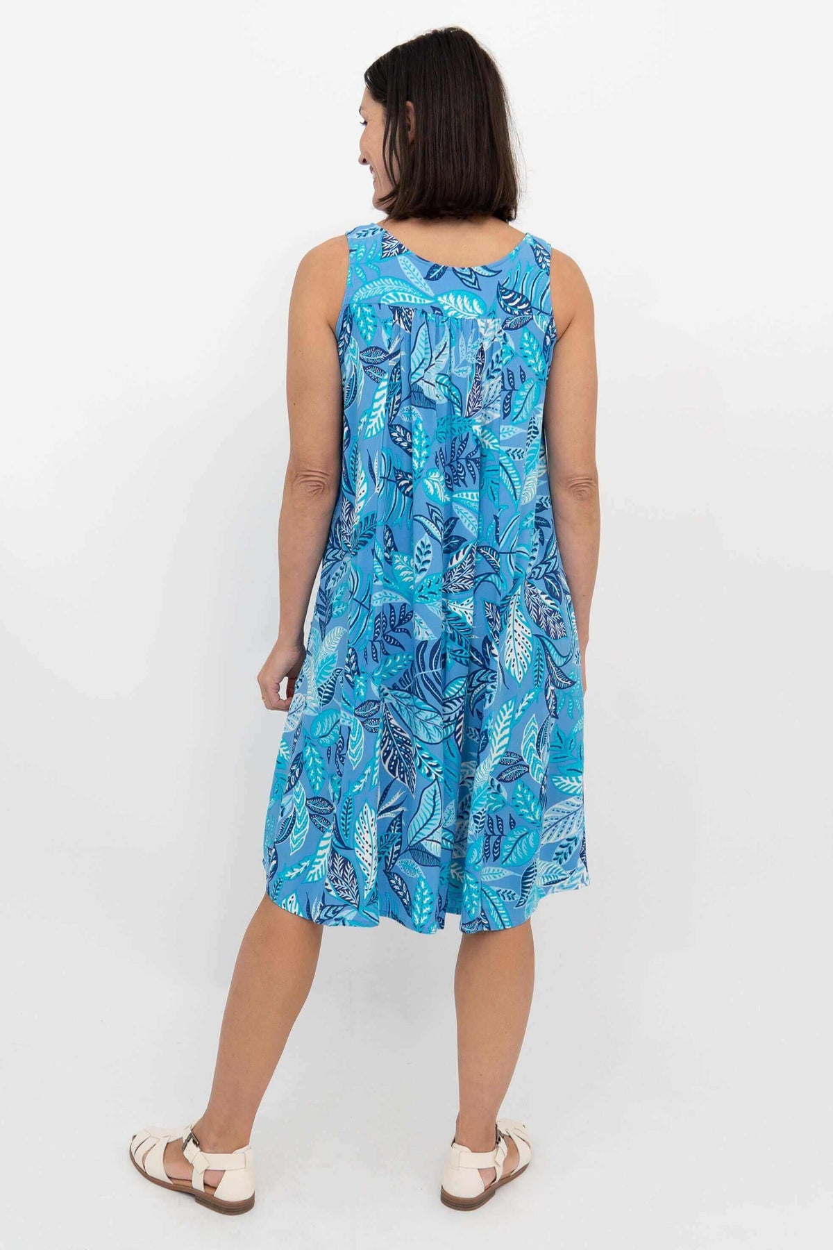 Back view of woman in sleeveless blue leaf print dress