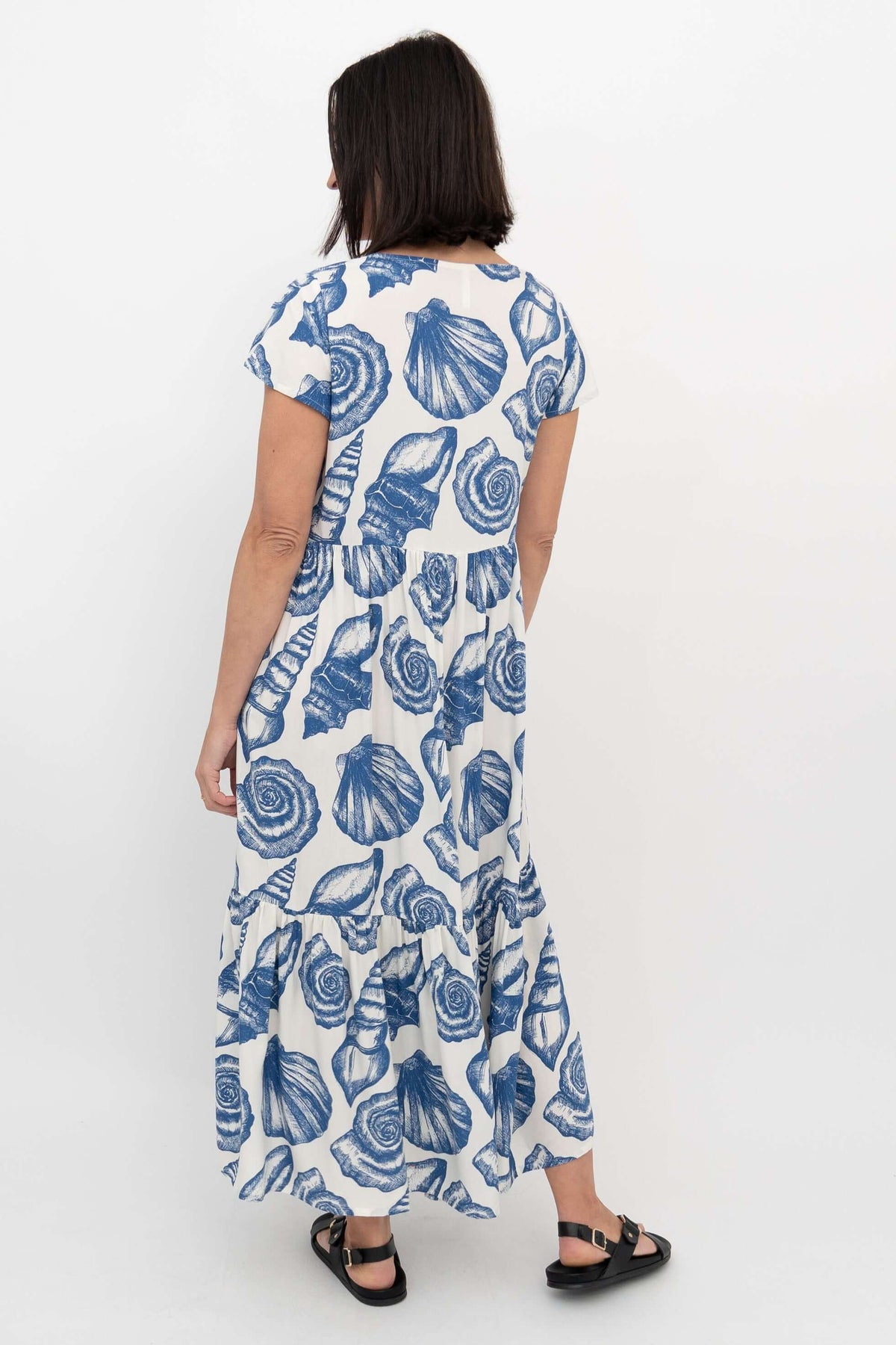 Back view of woman in white dress with blue seashell graphic print
