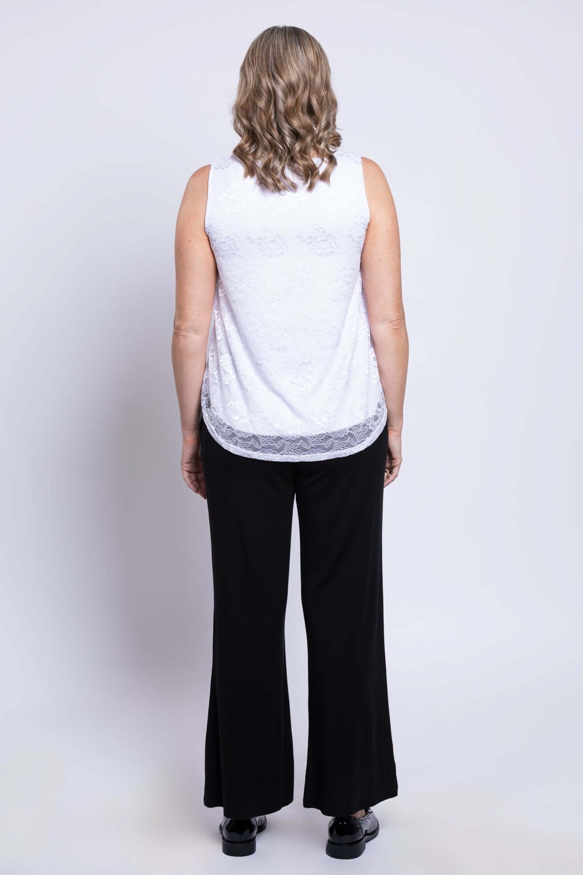 Back view of woman in white lace tank top with rounded hem