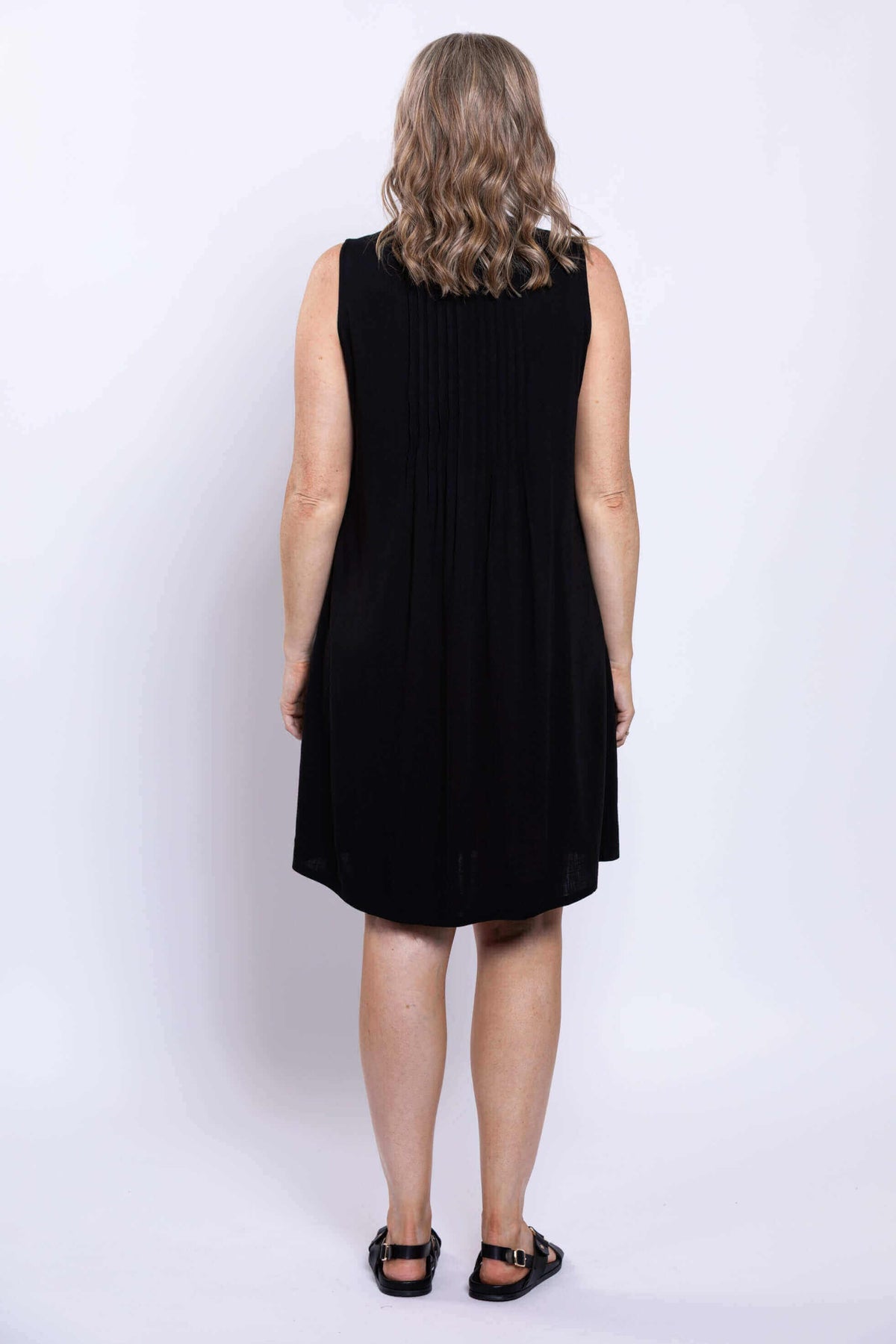 Back view of woman showing pintuck detailing on black sleeveless dress