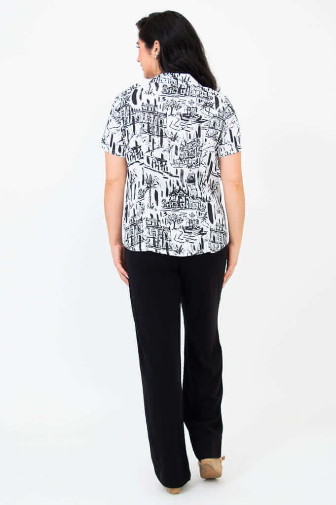 Back view of woman wearing black and white patterned shirt and black pants