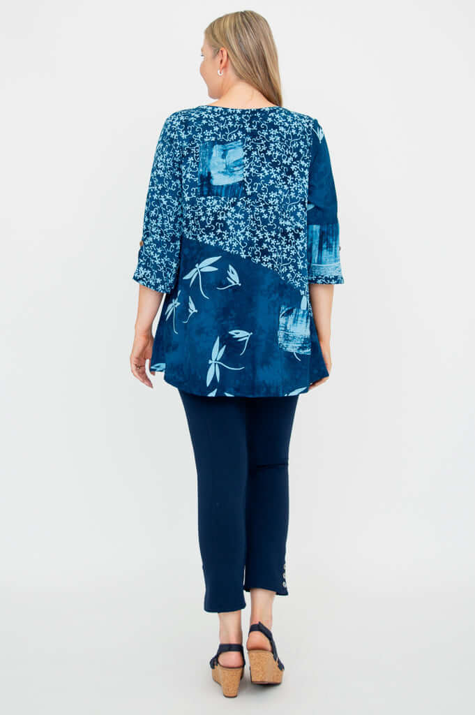 Back view of blue flowy blouse with floral and abstract prints worn by woman