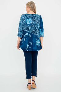 Back view of blue flowy blouse with floral and abstract prints worn by woman