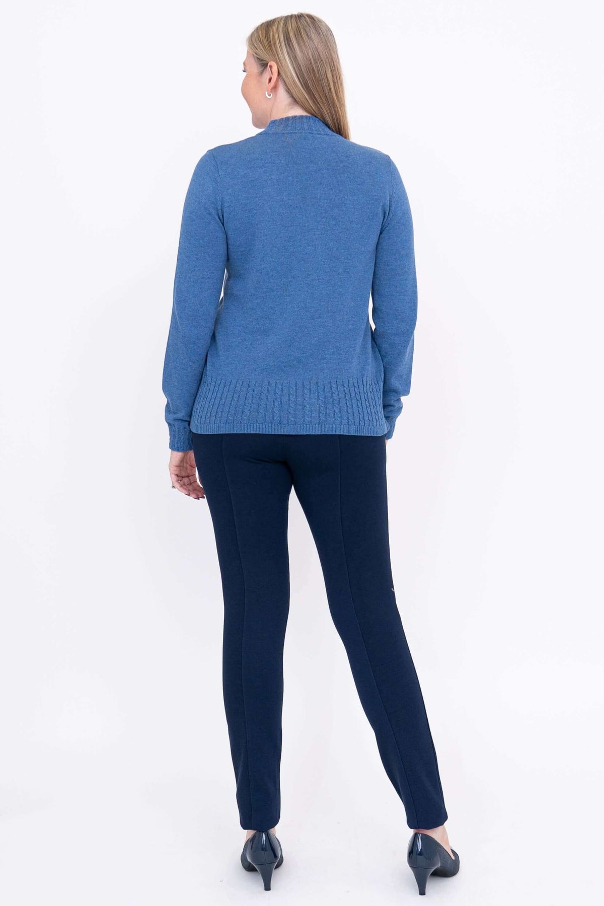 Back view of woman wearing blue cable knit sweater and navy pants