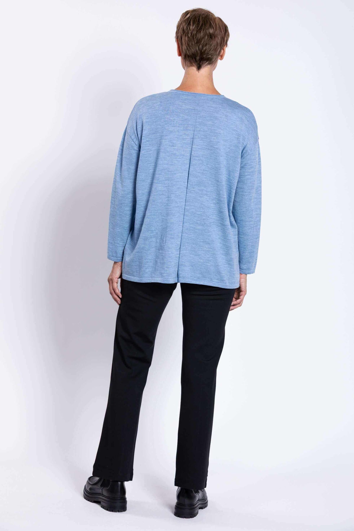 Back view of woman wearing light blue Merino wool sweater and black pants