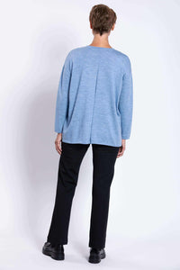 Back view of woman wearing light blue Merino wool sweater and black pants