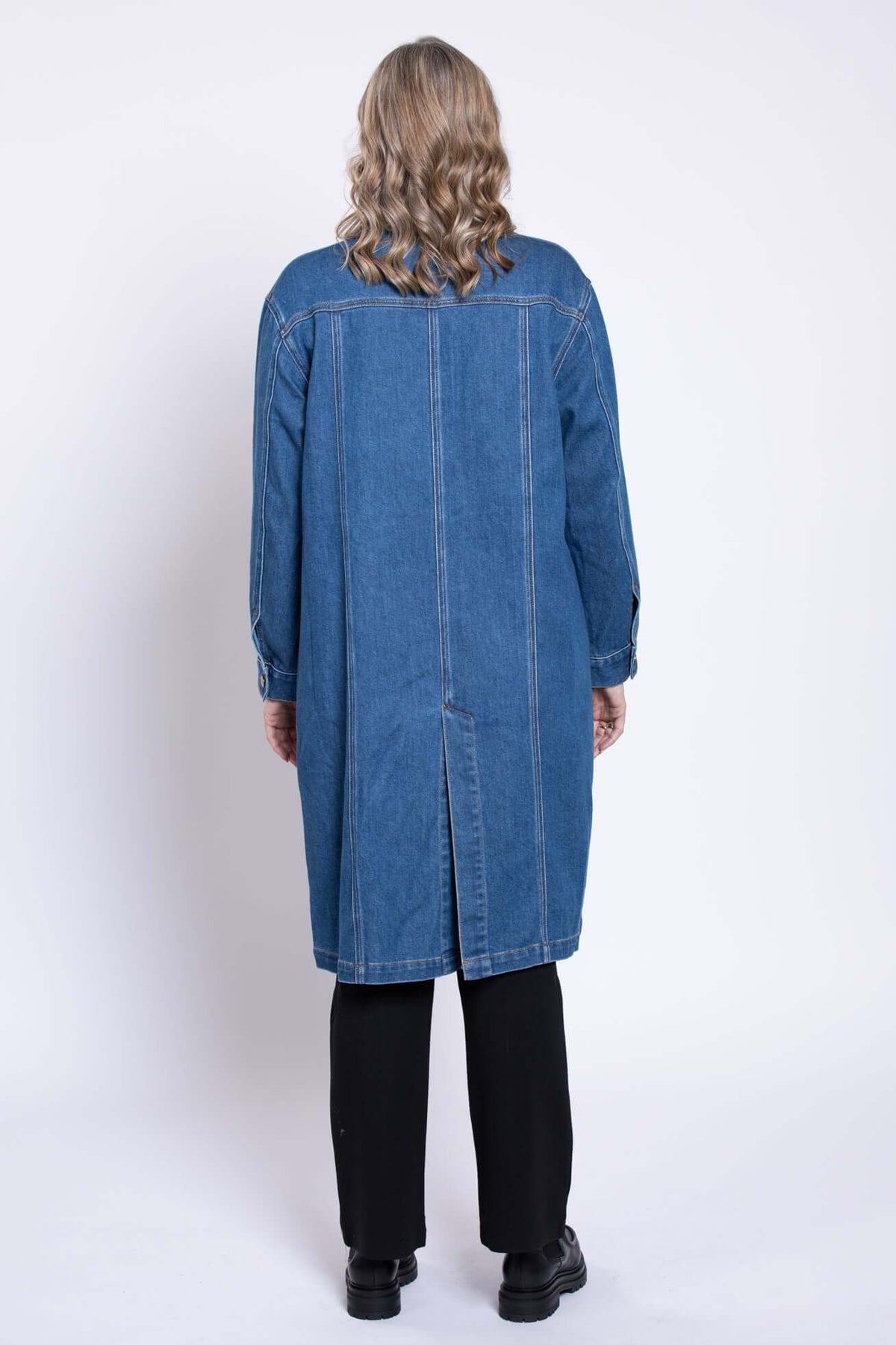 Back view of woman wearing longline denim jacket showing rear seams and split hem