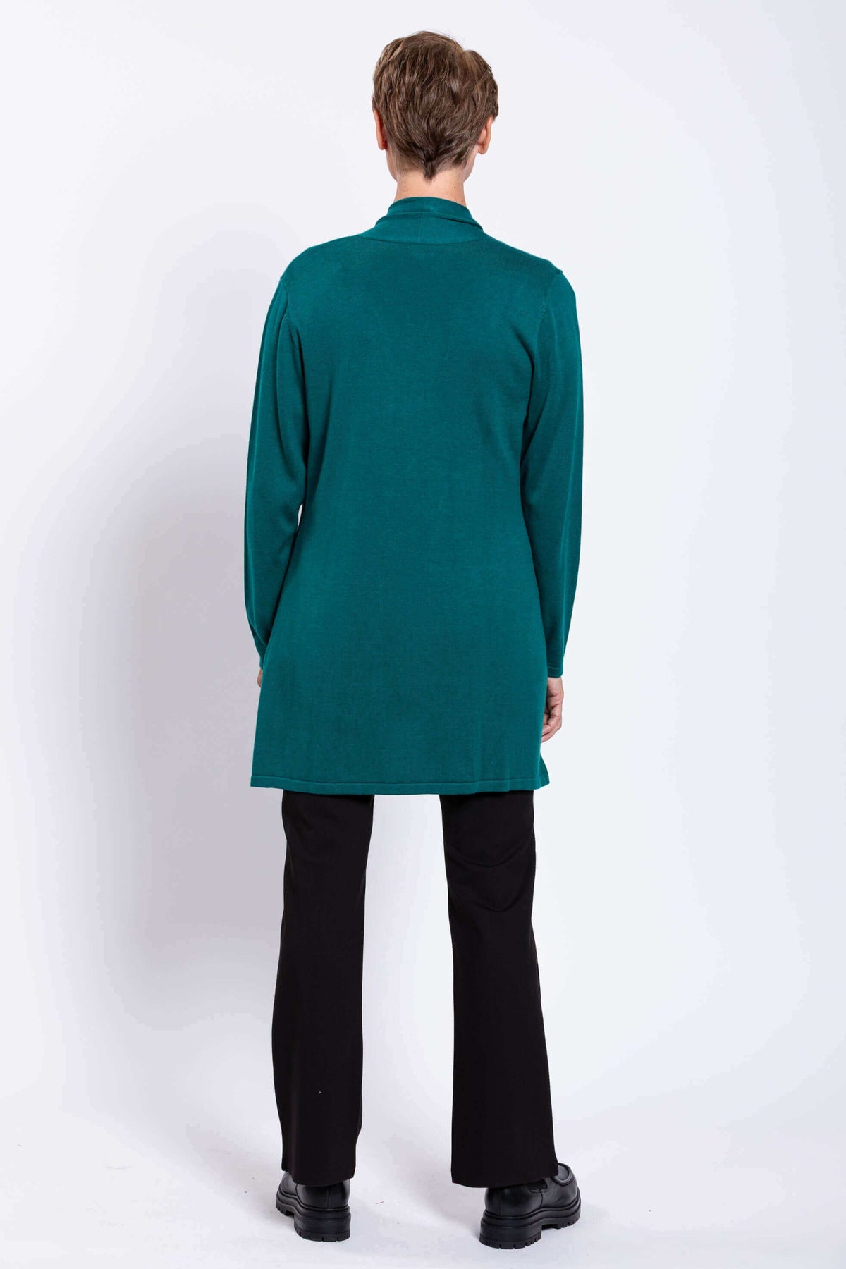 Back view of woman wearing teal cardigan over black pants