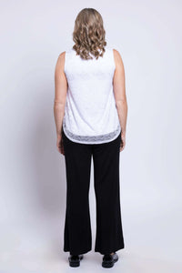 Back view of woman wearing white lace tank top and black pants