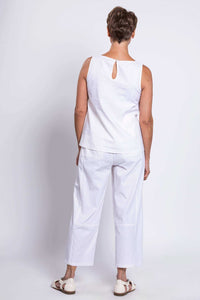 Back view of woman wearing white tank top with button closure and white pants