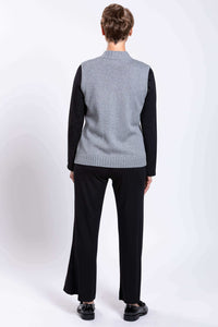 Back view of gray sleeveless zip vest worn by woman with short hair and black pants