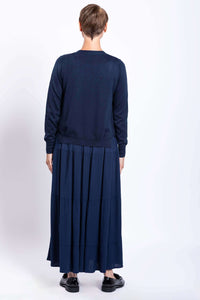 Full body back view of woman wearing dark blue knit sweater on a tiered flowy maxi skirt