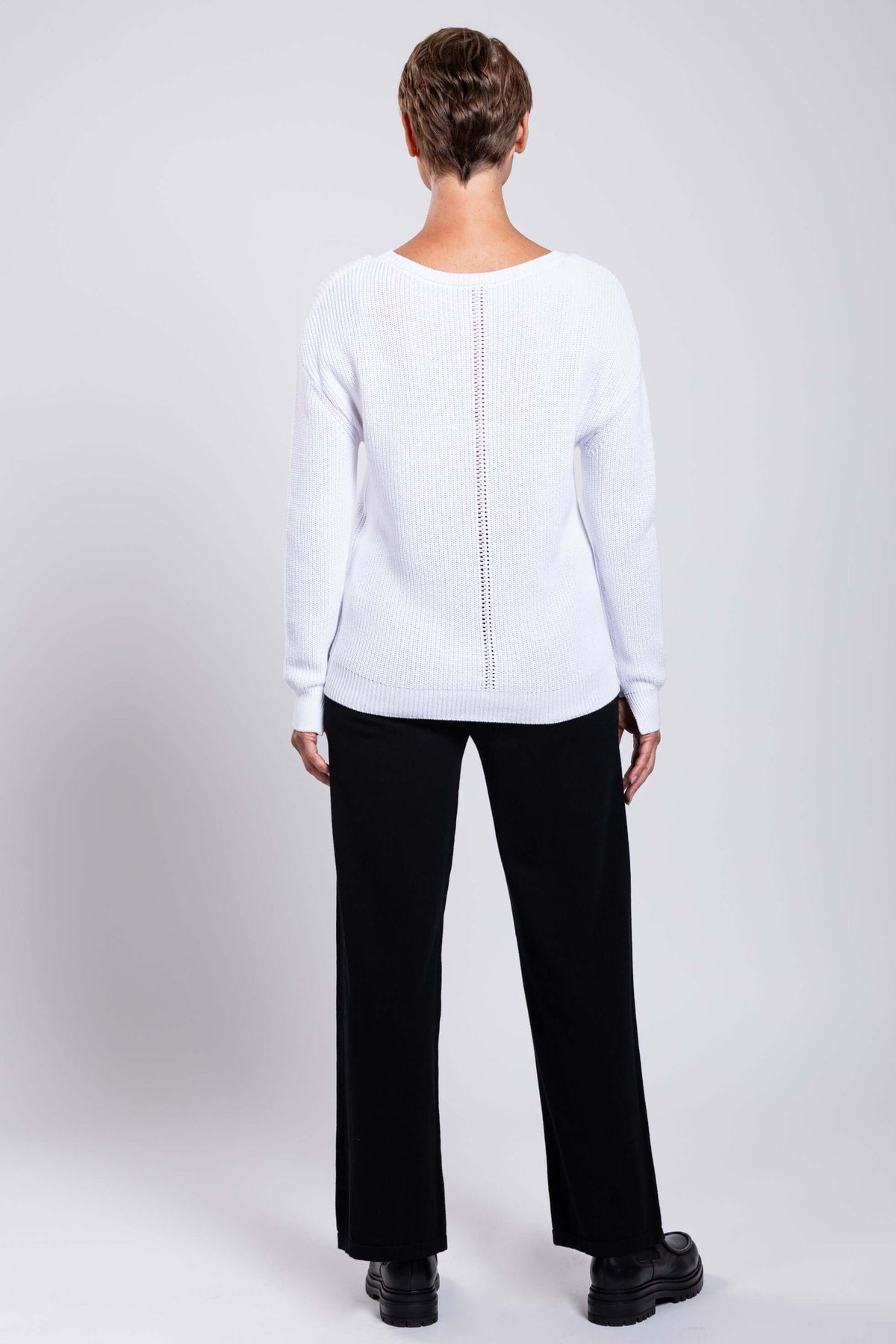 Back view of the model wearing a white cotton sweater with center seam detail