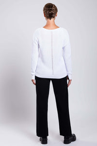 Back view of the model wearing a white cotton sweater with center seam detail