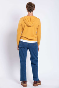 Back view of a woman wearing a mustard yellow wool cashmere zip hoodie showing attached hood fit.