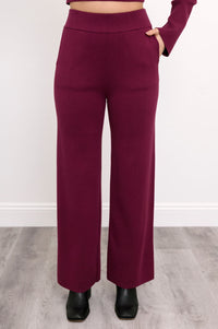 Close-up front view of women's relaxed-fit maroon track trousers, highlighting the straight-leg silhouette.