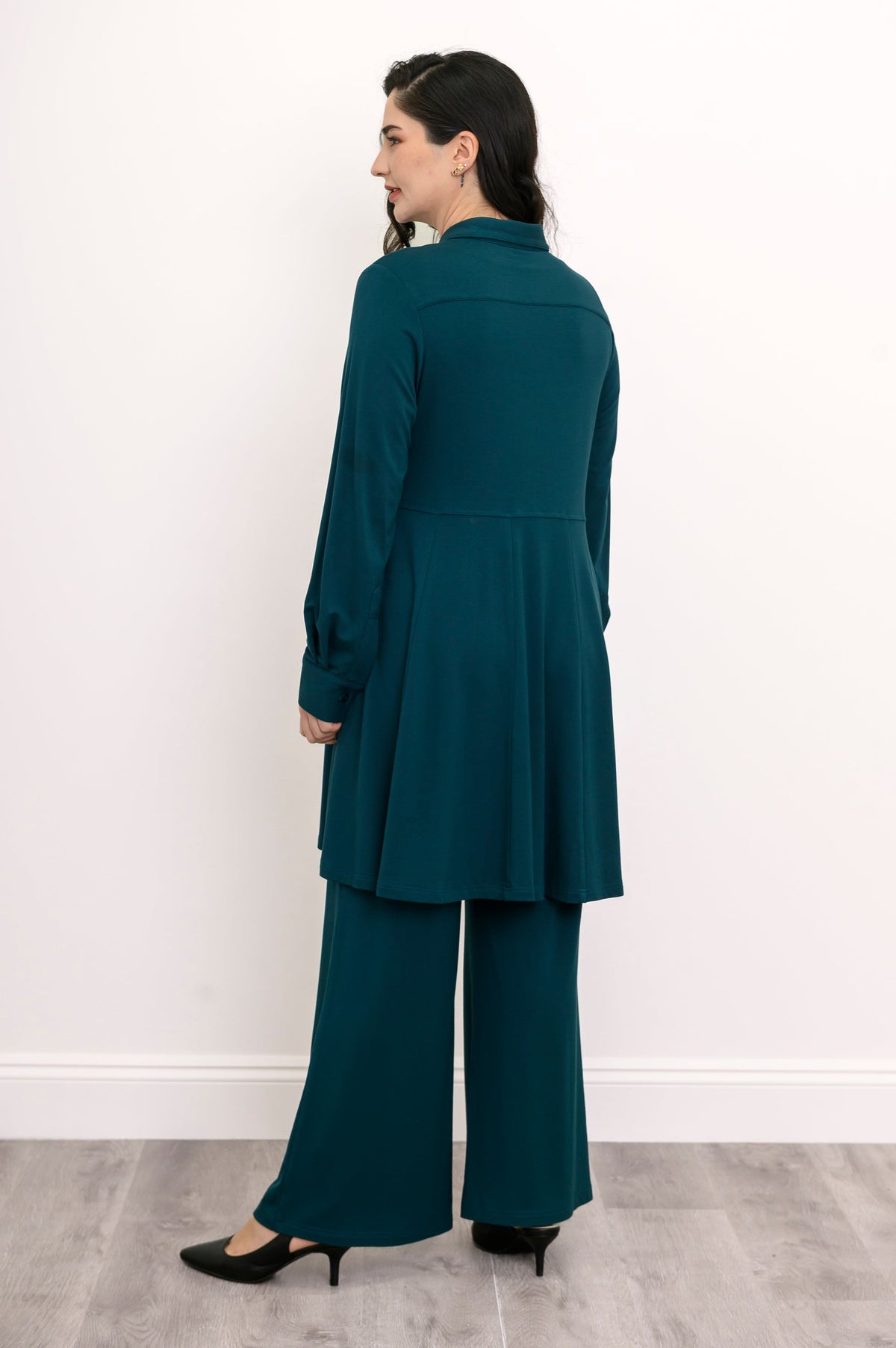 Straight-on back portrait of a women's teal long-sleeve knit tunic blouse with a skirted bottom.