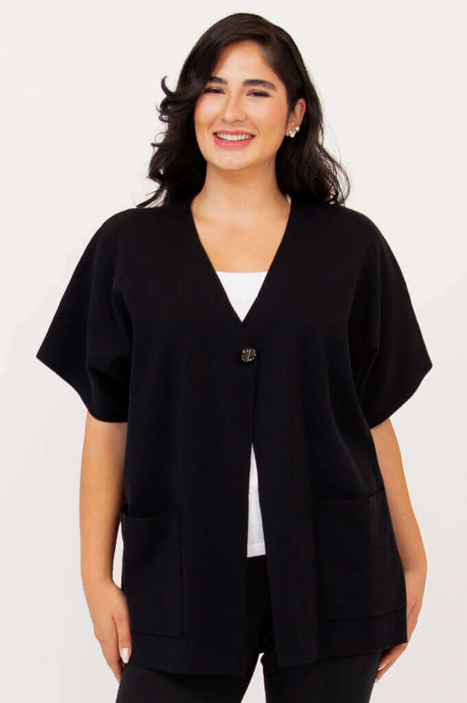 Woman wearing a black cotton cardigan with large front pockets and cropped sleeves, front view