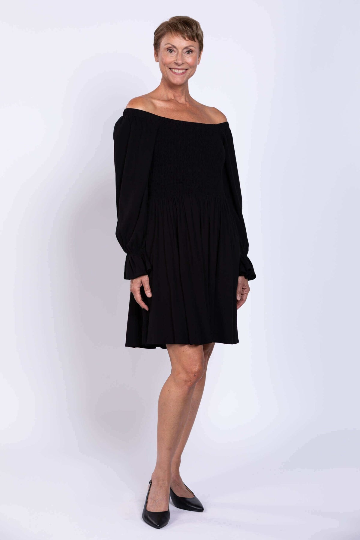 Woman modeling a black dress with off-the-shoulder sleeves and knee-length skirt