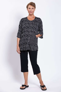 Woman with hand in front pocket, showcasing the unique abstract patterned blouse