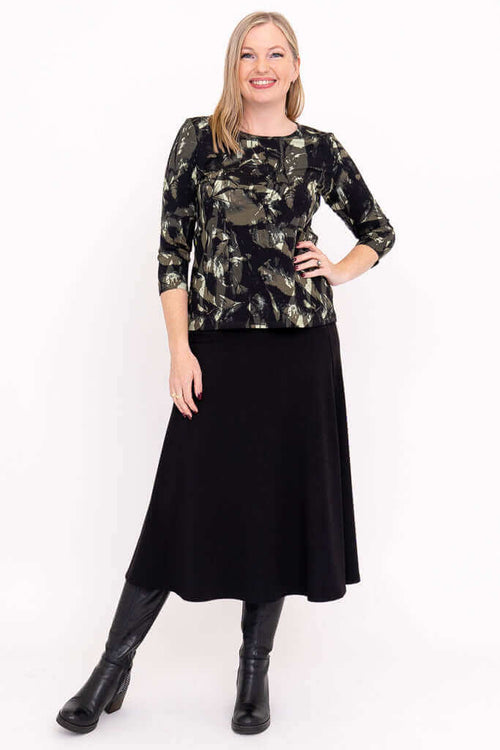Woman modeling a black brushstroke top paired with a black skirt and boots