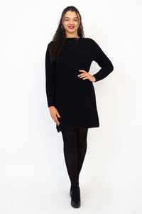 Woman wearing a black cable knit sweater dress, facing forward with a smile
