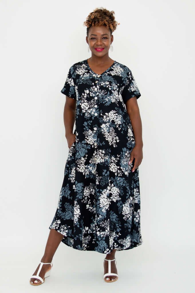Black floral A-line dress, front view, model with hands in pockets