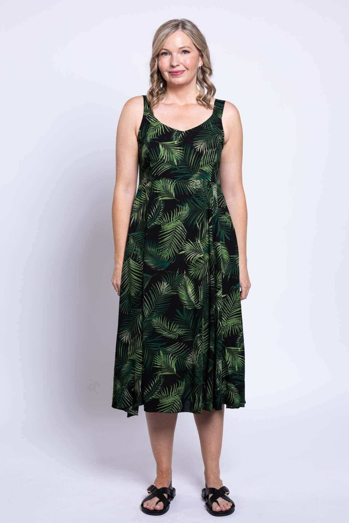 Woman in black green leaf print dress styled with a black shrug