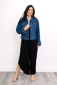 Model wearing black jumpsuit with denim jacket and block heel shoes