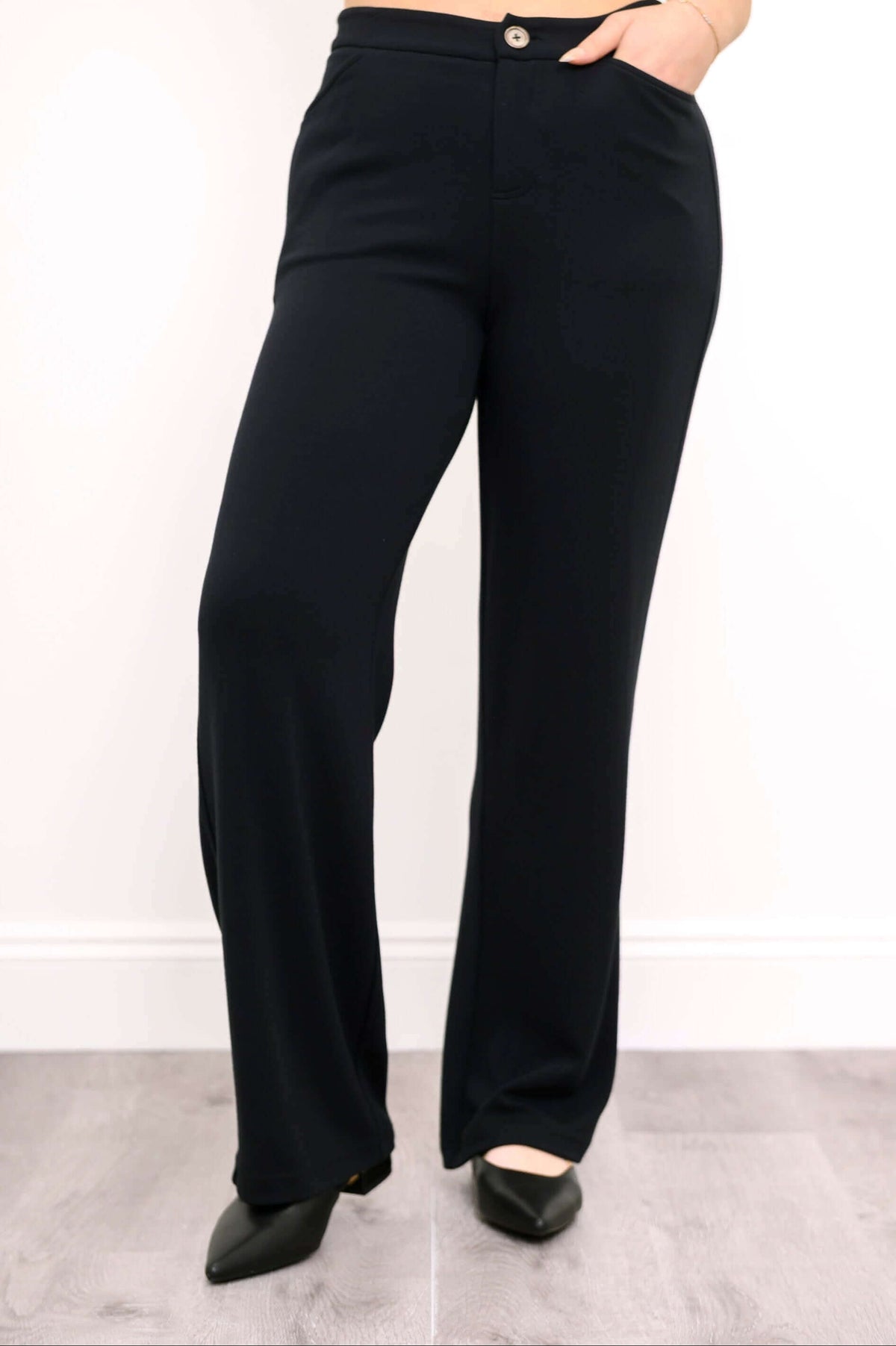 Front view of black high-waisted straight leg pants with hand in pocket