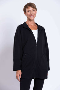 Smiling woman wearing a black zip-up jacket with dolman sleeves and front zip pockets