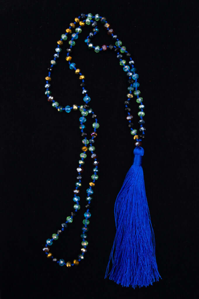Blue crystal mala necklace with multicolor faceted beads and vibrant blue tassel on black background