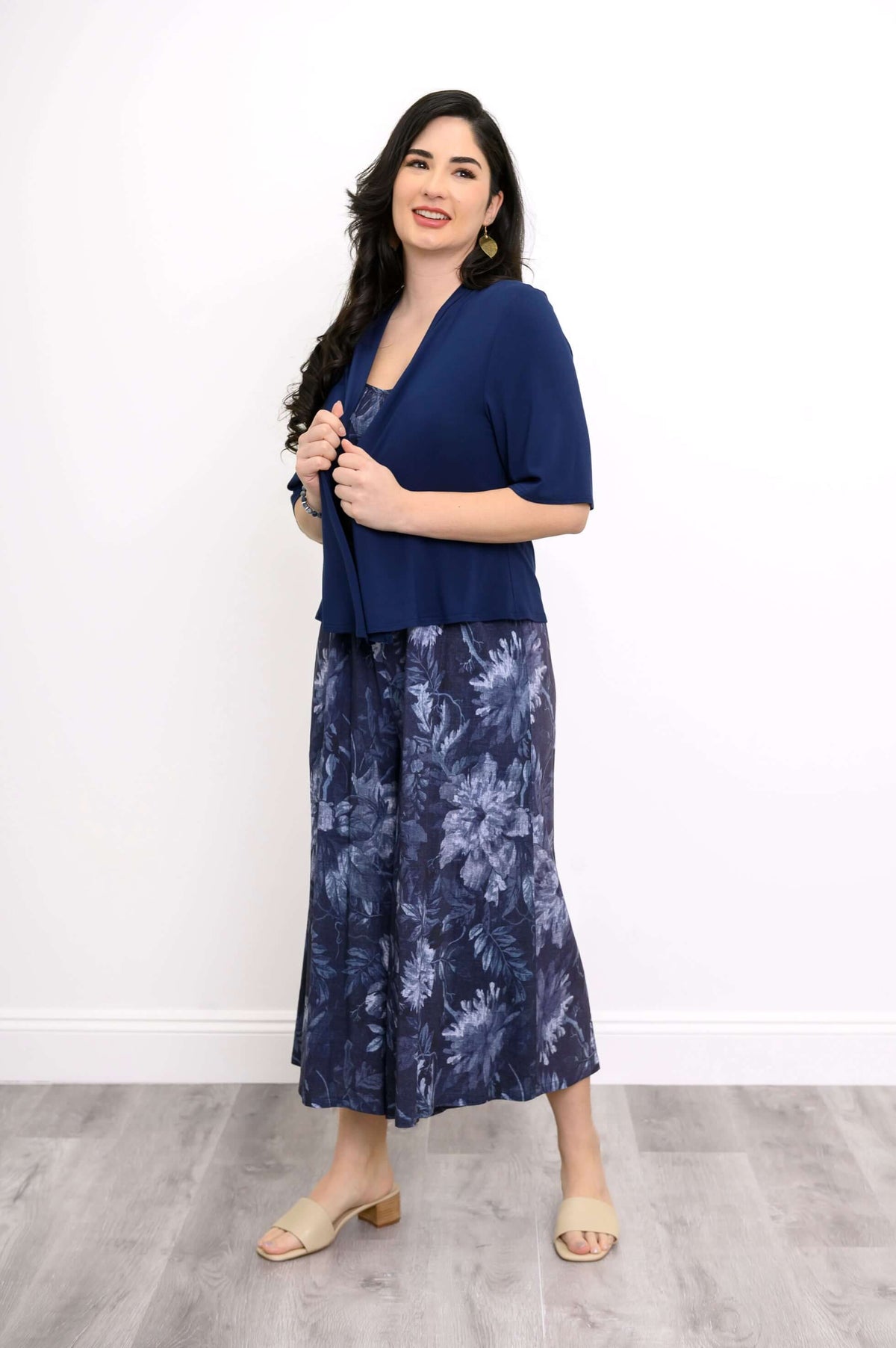 Woman wearing a blue floral jumpsuit paired with a navy short-sleeve cardigan