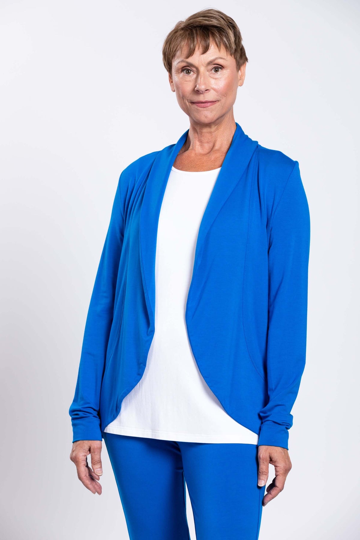 Woman wearing a blue shawl collar French Terry jacket over a white top, front view