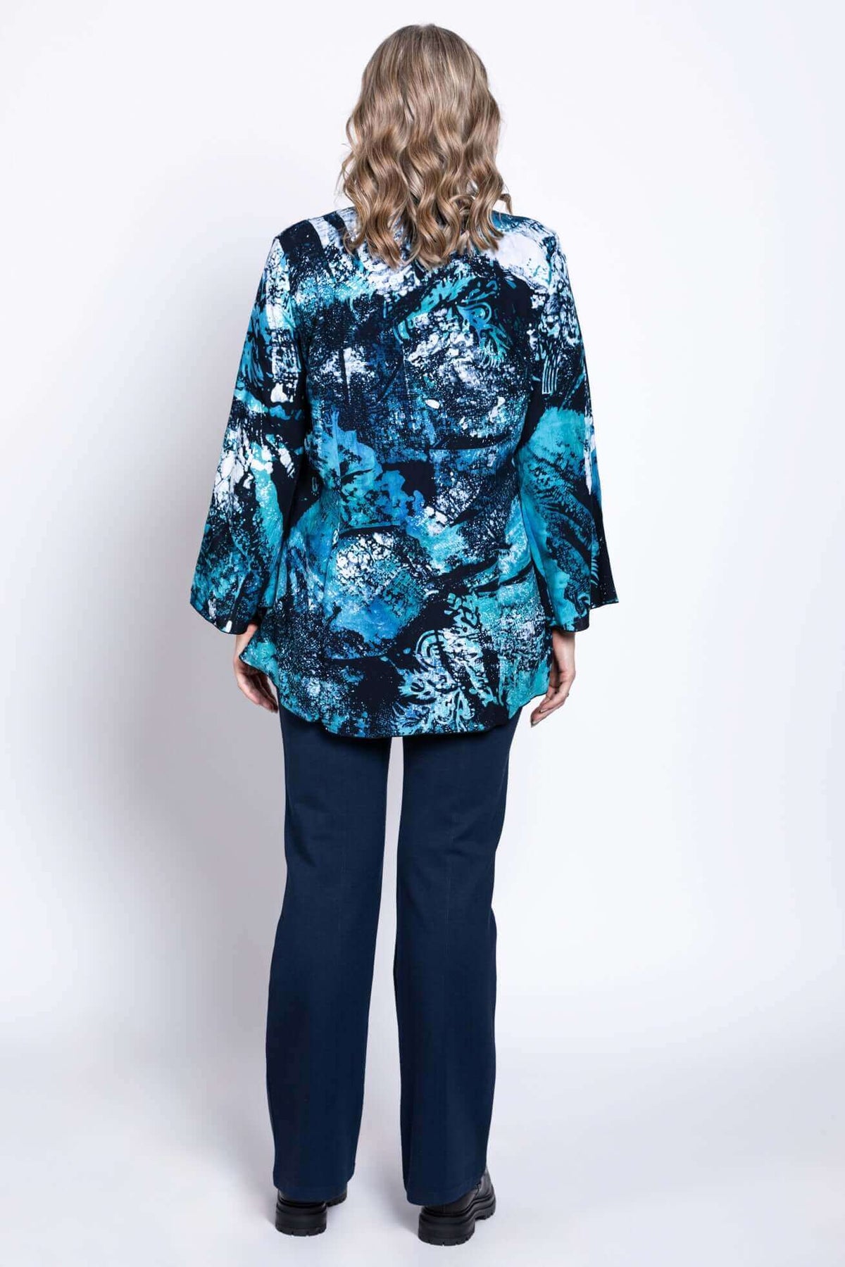Back view of woman in blue and black abstract print blouse and navy pants